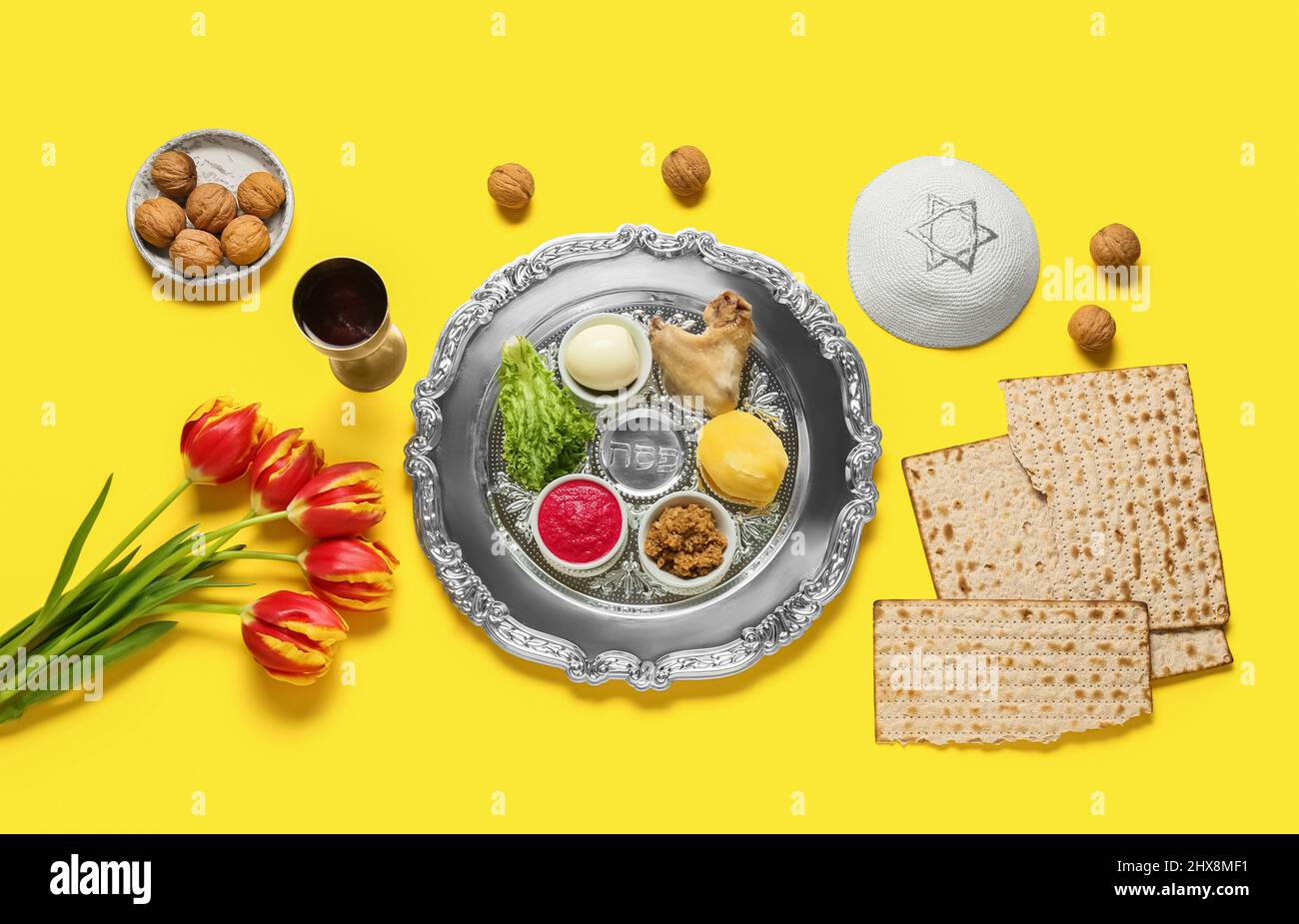 Passover Seder plate with traditional food, flowers and kippah on color ...