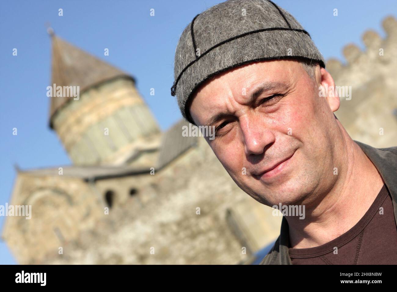 The man poses in national georgian hat on church background in Georgia Stock Photo