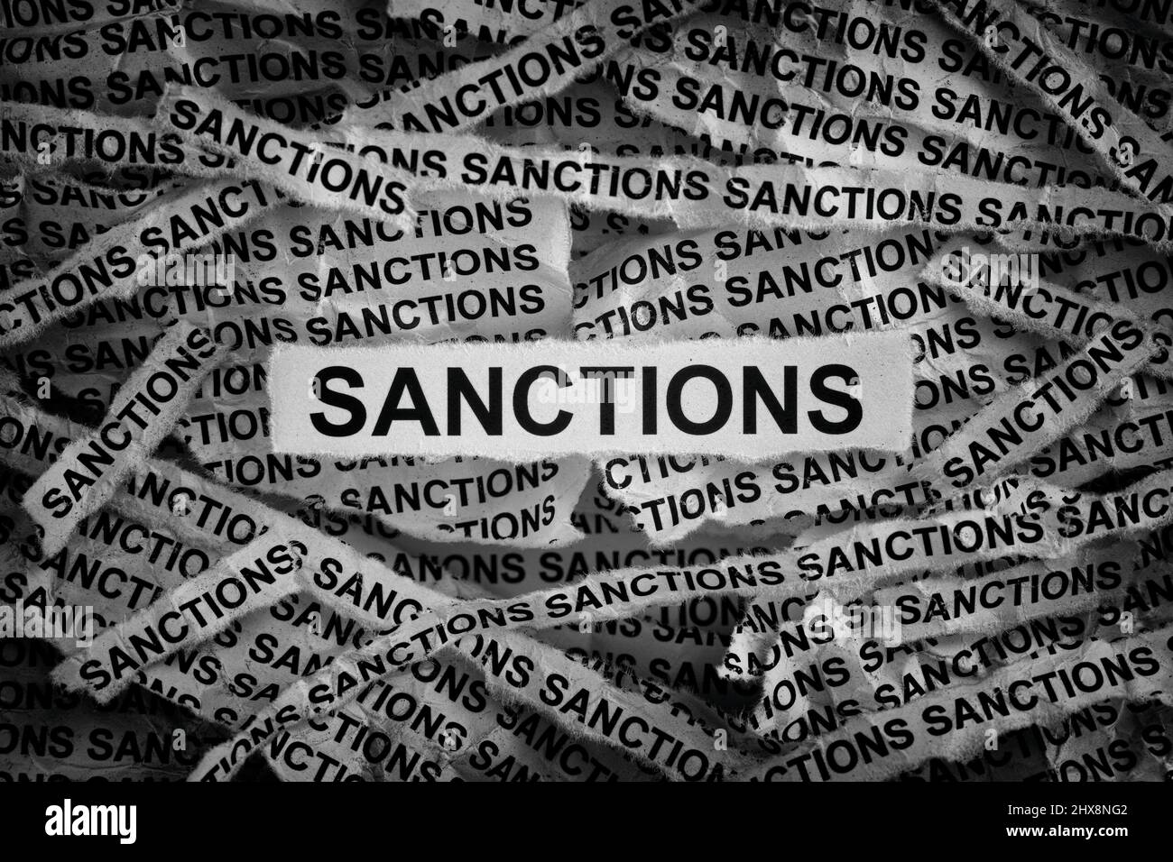 Strips of newspaper with the words Sanctions. Black and white. Close up. Stock Photo