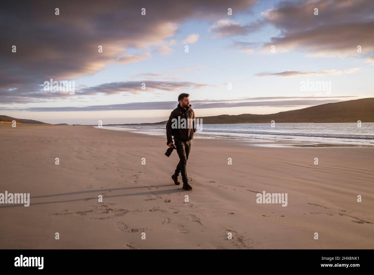 A photographer exploring the Luskentyre beach in Isle of Harris during sunset. Stock Photo
