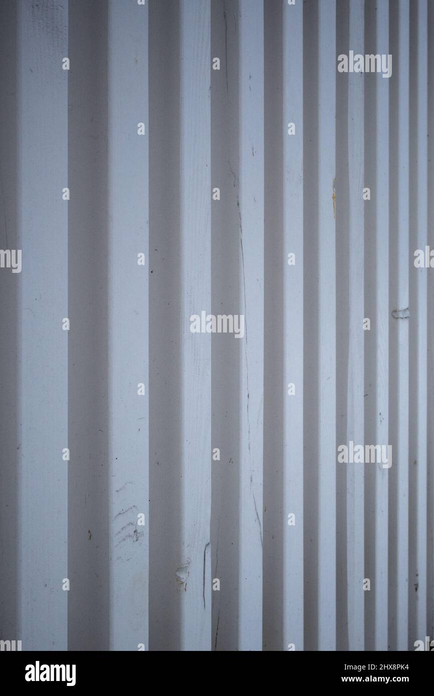 Abstract background consisting of white metal strips. Vertical fence made of metal slats. Pattern of stripes with a blurred background. Painted and te Stock Photo