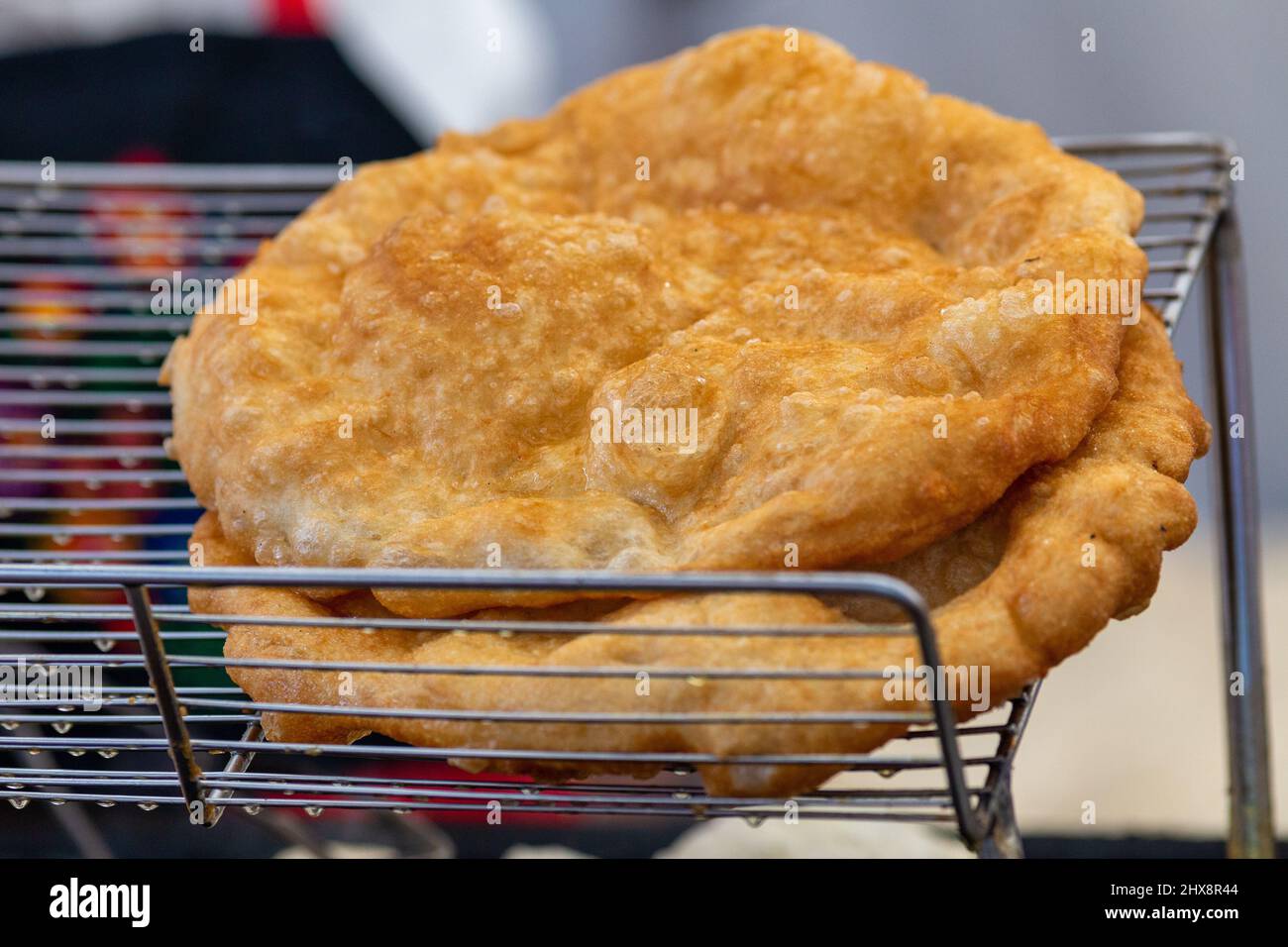 Freshly baked langos offered on the market. Hungarian speciality, a deep fried flat bread made of potato-based dough offered on the market. Stock Photo