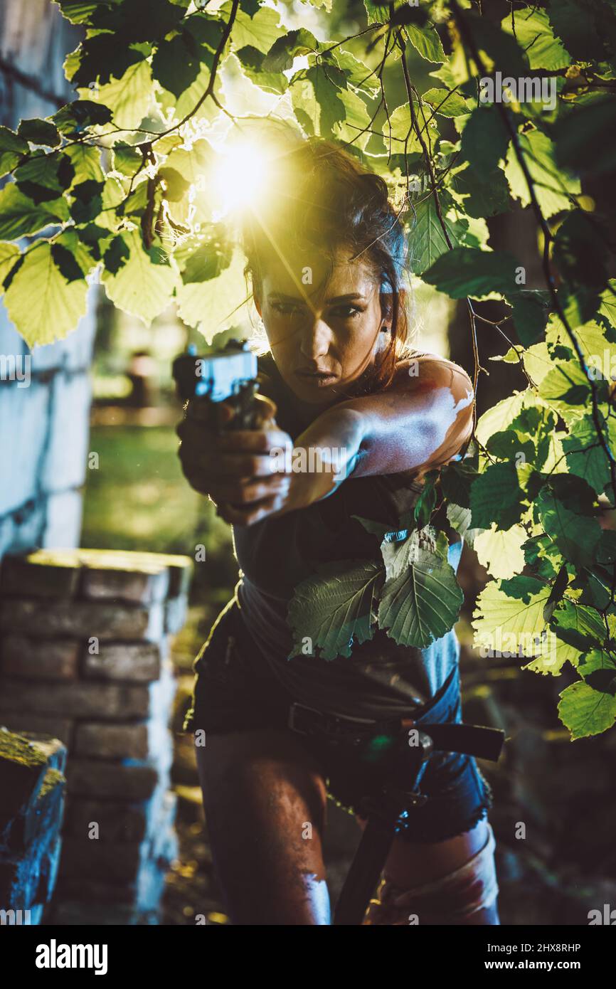 Beautiful soldier woman holding gun and getting ready for the attack in nature. Stock Photo