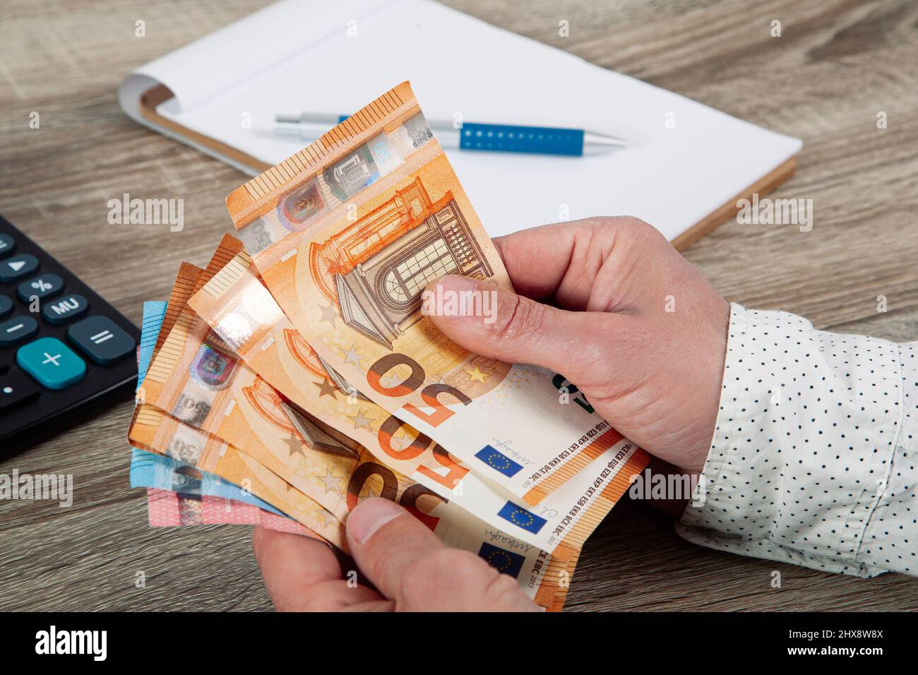 saving, finance, economy and housing concept - man hands with calculator counting money and making notes at home Stock Photo