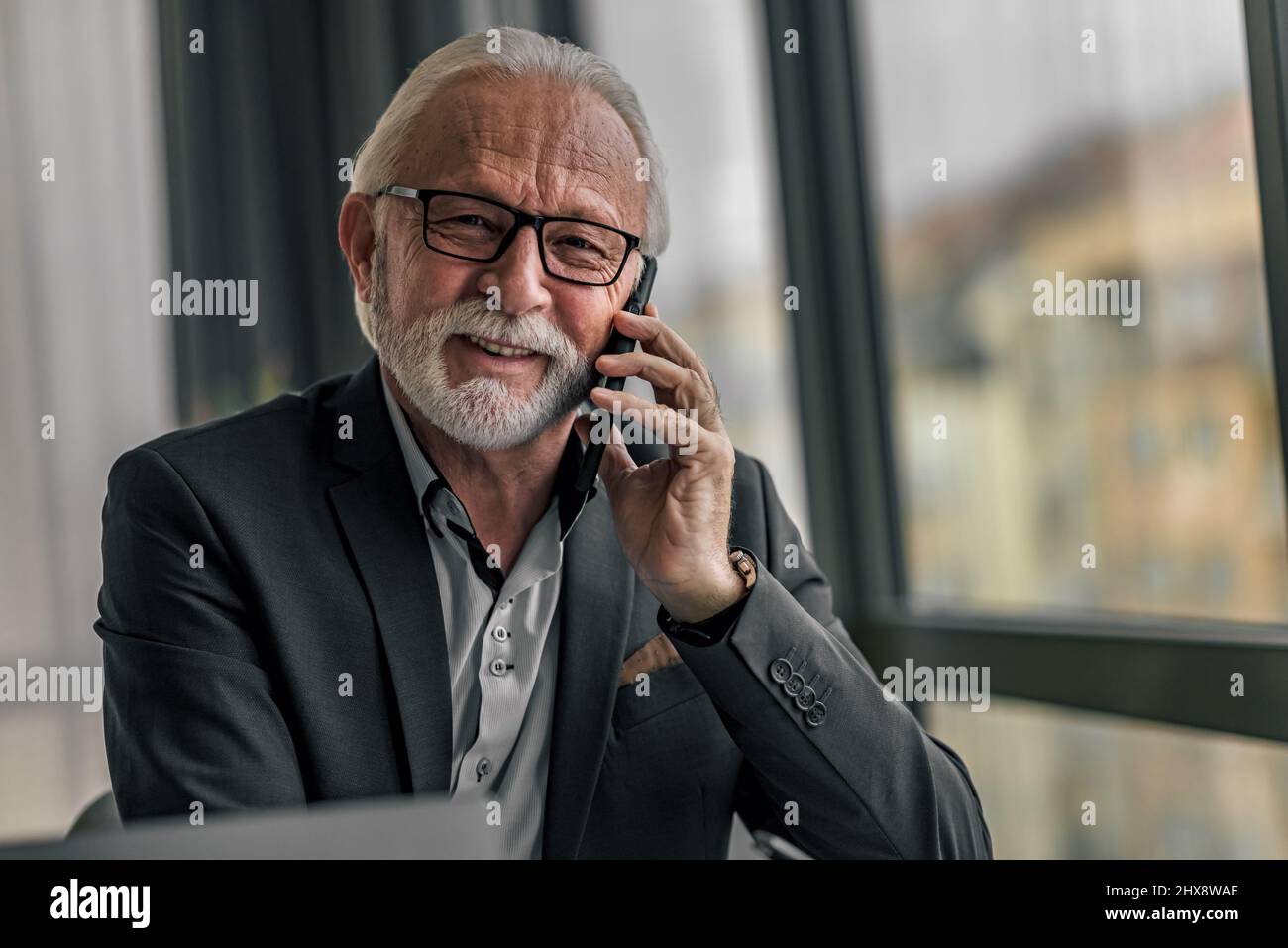 Handsome senior man businessman entrepreneur making a phone call looking at camera Stock Photo