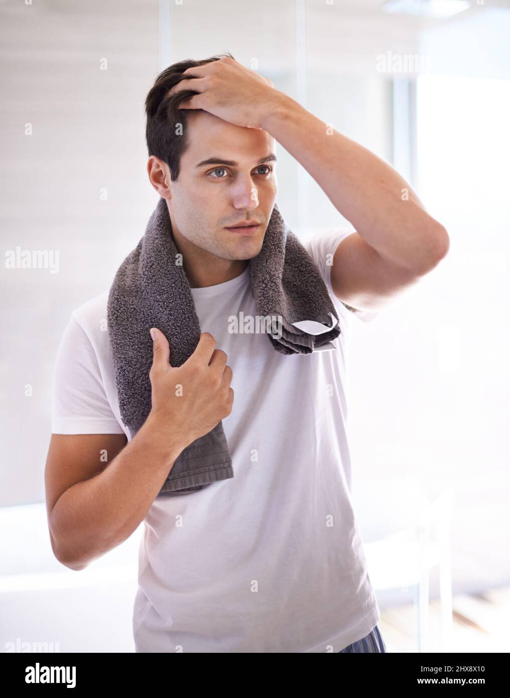 Time to shower and get shaved. Cropped shot of a young man in the bathroom with a towel around his neck. Stock Photo