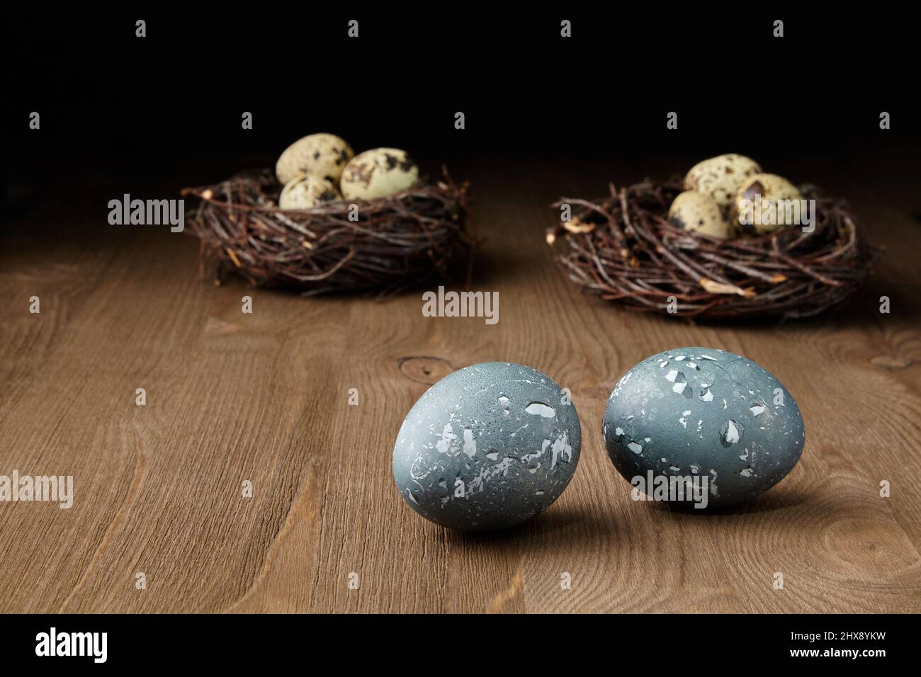 .Painted chicken and quail eggs in nests on a brown wooden table ...