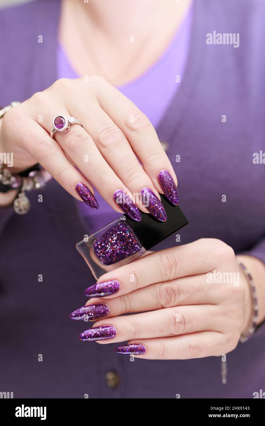 Female hand with long nails and purple plum manicure holds a bottle of nail  polish Stock Photo - Alamy