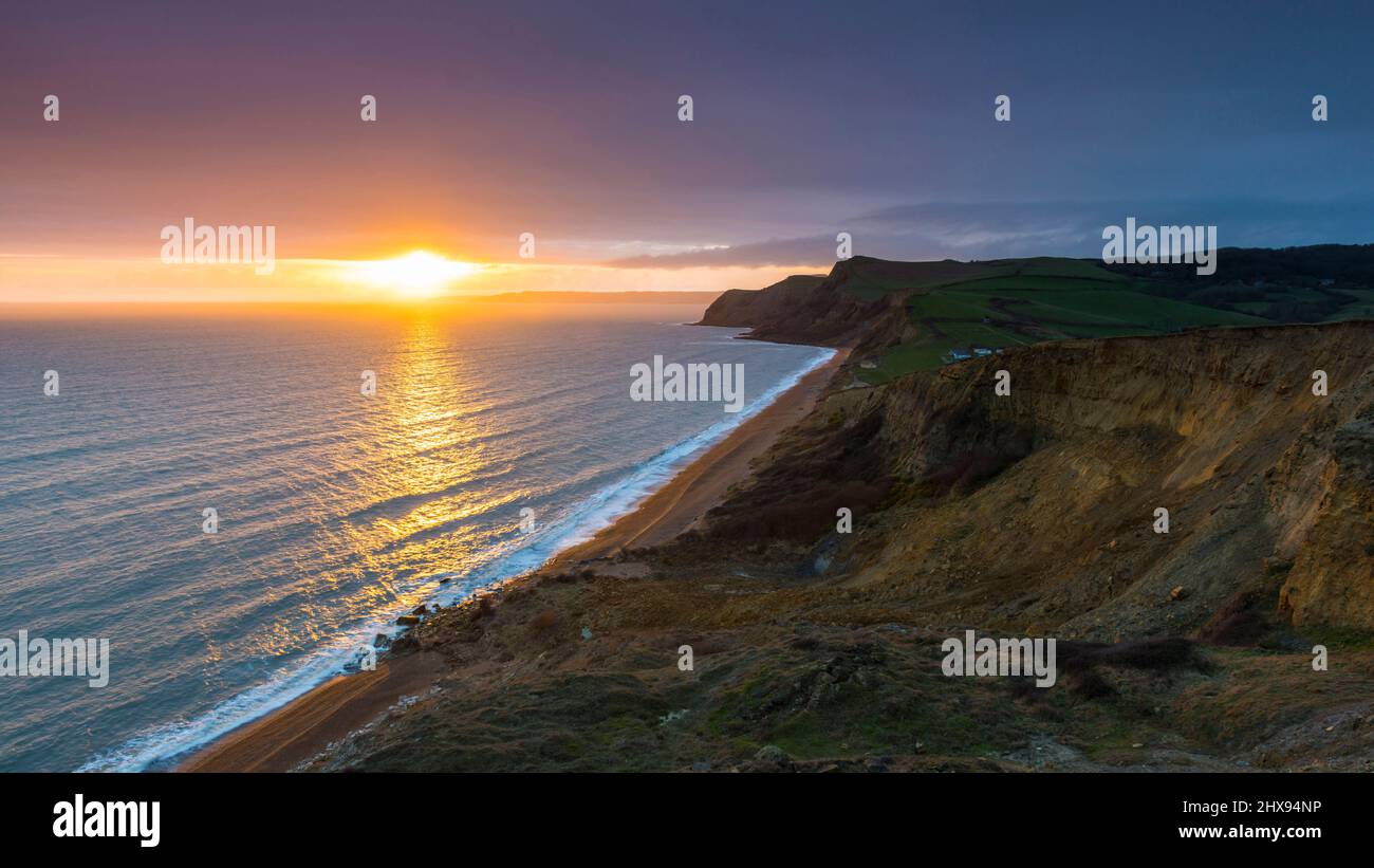 Eype, Dorset, UK.  10th March 2022.  UK Weather.  View along the beach and cliffs at Eype on the Dorset Jurassic Coast as the sun shines through a break in the clouds shortly before sunset.  Picture Credit: Graham Hunt/Alamy Live News Stock Photo