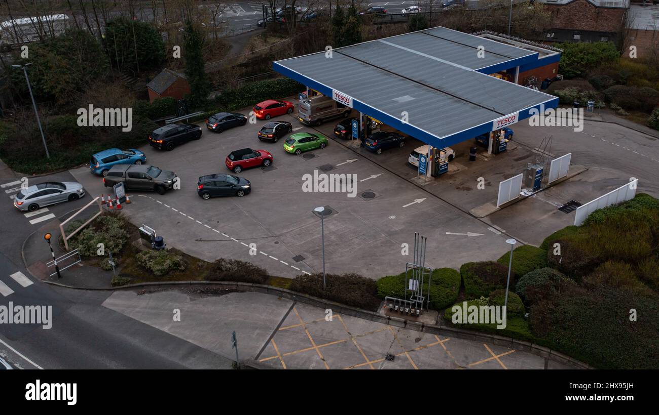 Wigan, UK: March 10, 2022: Aerial View. Queuing cars waiting to buy fuel at a Tesco petrol filling station as British drivers panic buy fuel Stock Photo