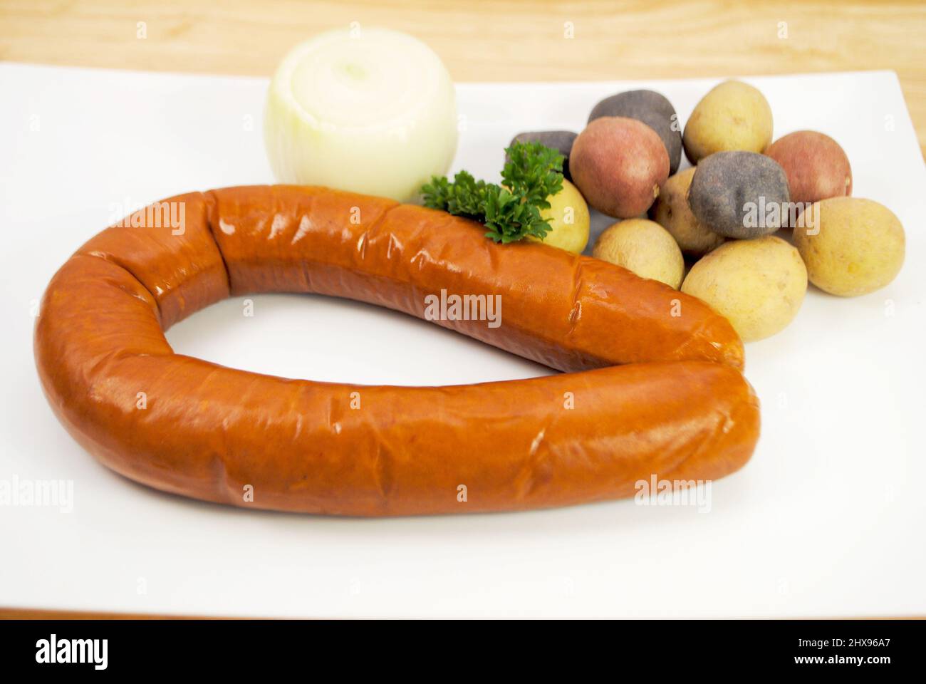 Spicy Whole Smoked Kielbasa, with Tri0colored Potatoes and an Onion Stock Photo