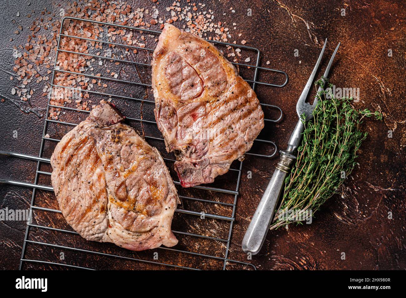 BBQ Grilled Pork loin steaks from neck fillet meat on grill. Dark
