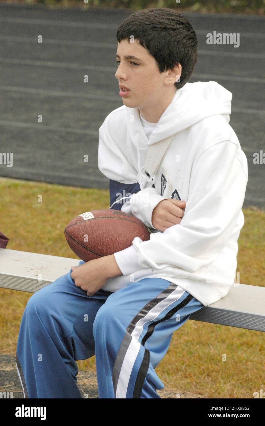 Injured young football player on bench with arm in cast from injurie