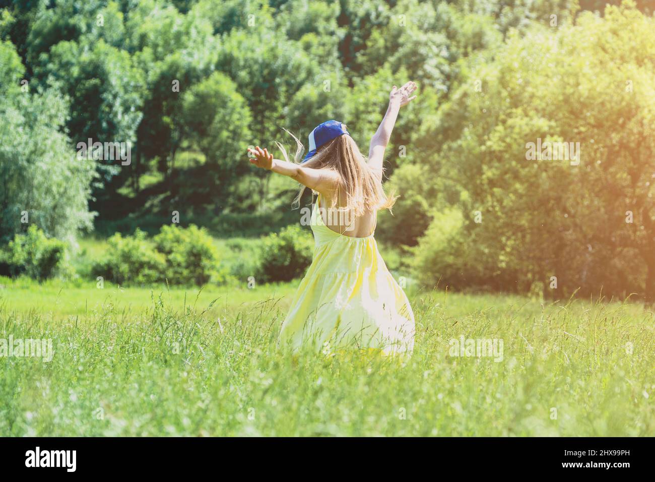 A girl in a yellow dress runs on a green meadow Stock Photo - Alamy