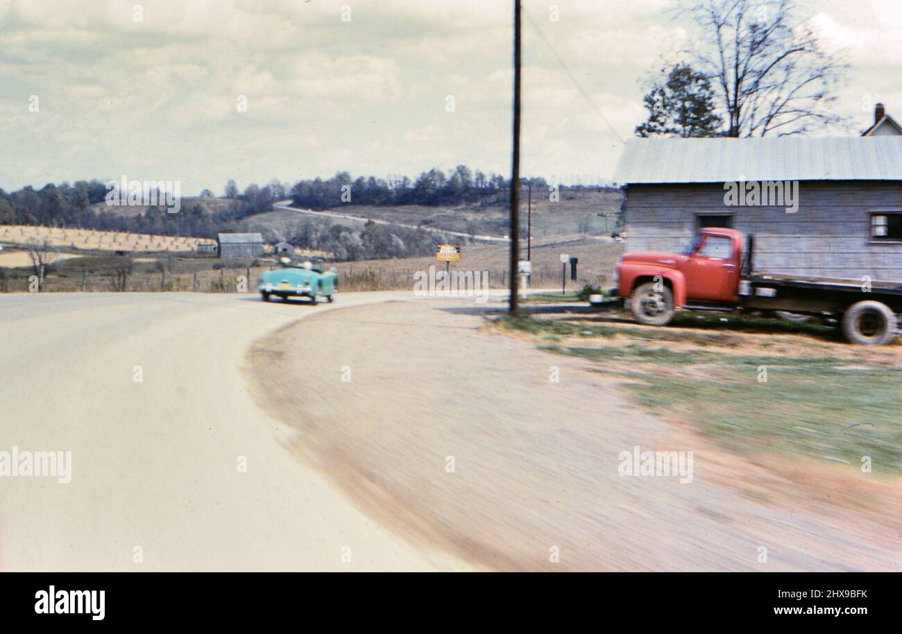 Man and woman driving down a rural road in a pastel blue convertible