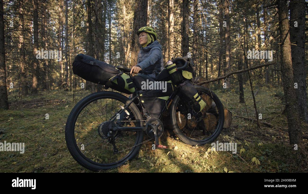The woman travel on mixed terrain cycle touring with bike bikepacking outdoor. The traveler journey with bicycle bags. Stylish bikepacking, bike, spor Stock Photo