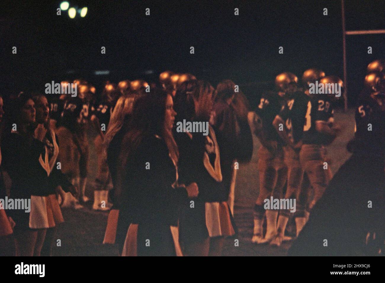 High school cheerleaders during a night football game ca. 1974 Stock Photo