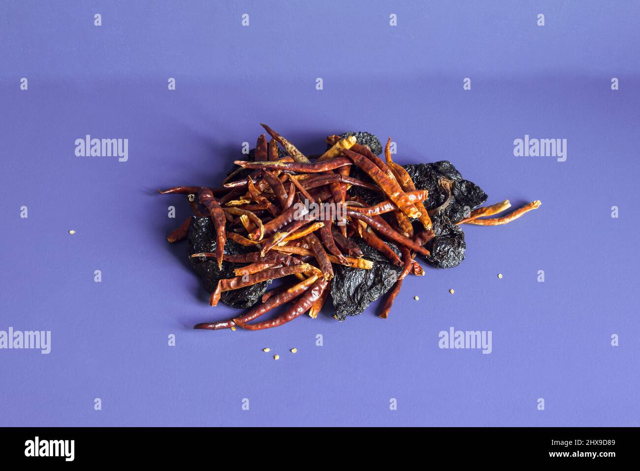 A pile of dehydrated chili peppers with dried ñora peppers on a textured color studio background. Still life and abstract decorations. Stock Photo