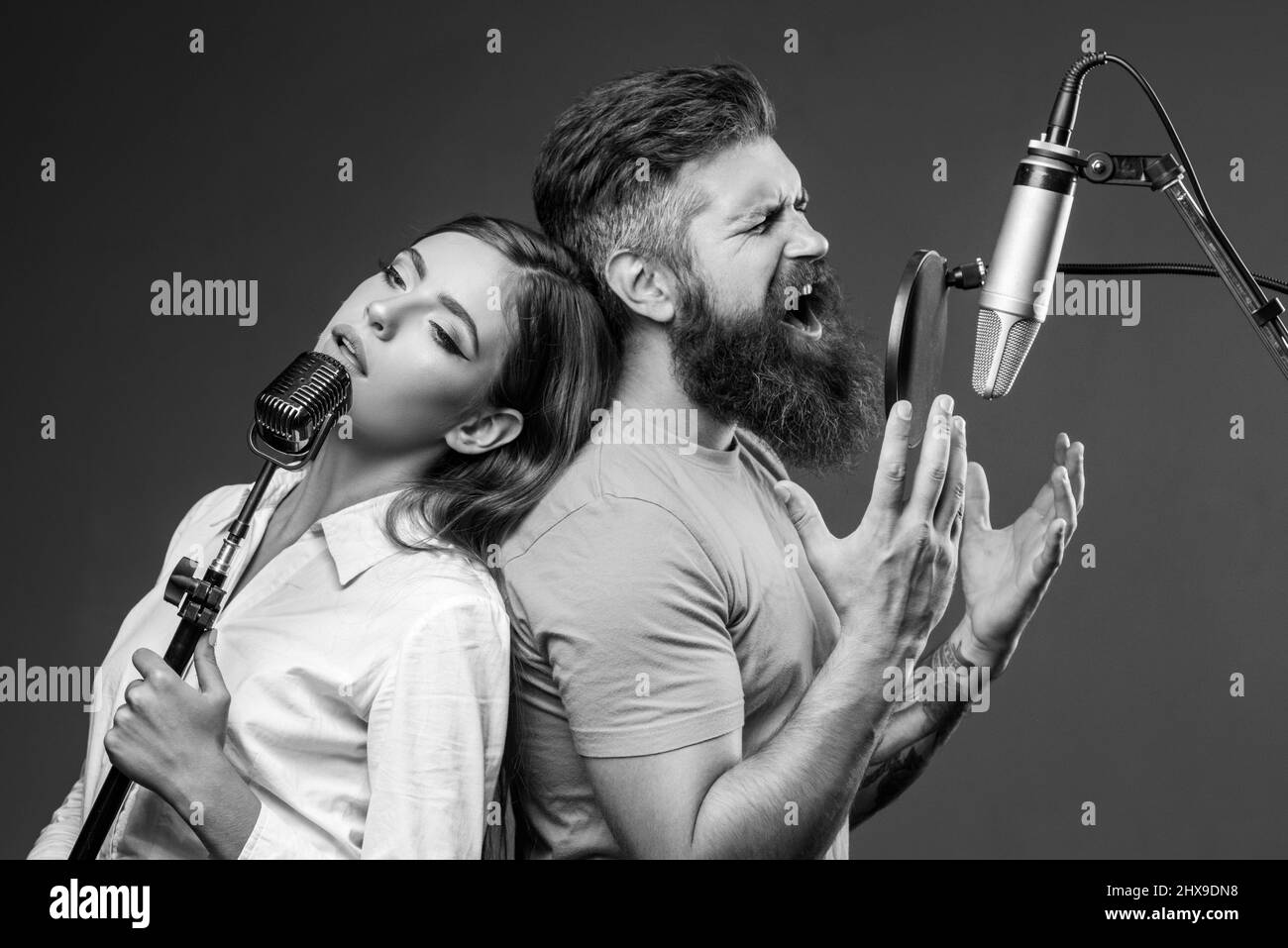 Singer couple singing rock. Sound producer recording song in a music studio. Excited duet