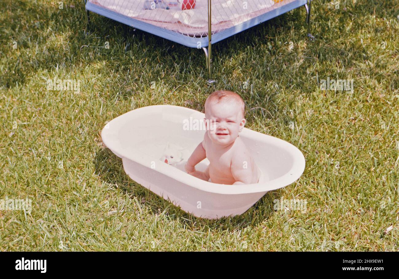 Twelve month old baby girl sitting outside in a bathtub ca. 1964 Stock