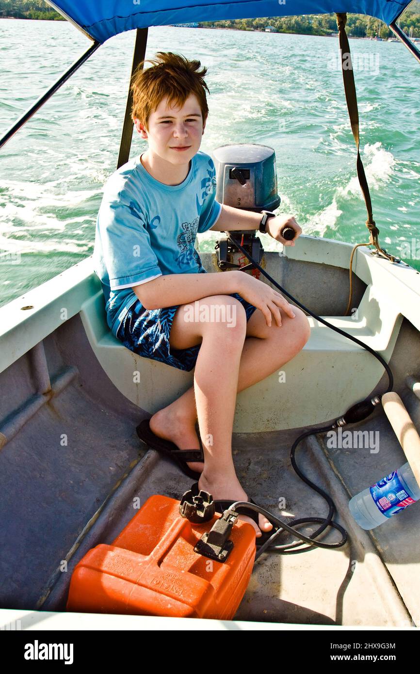 joung boy with red hair is steering the boat over the sea Stock Photo
