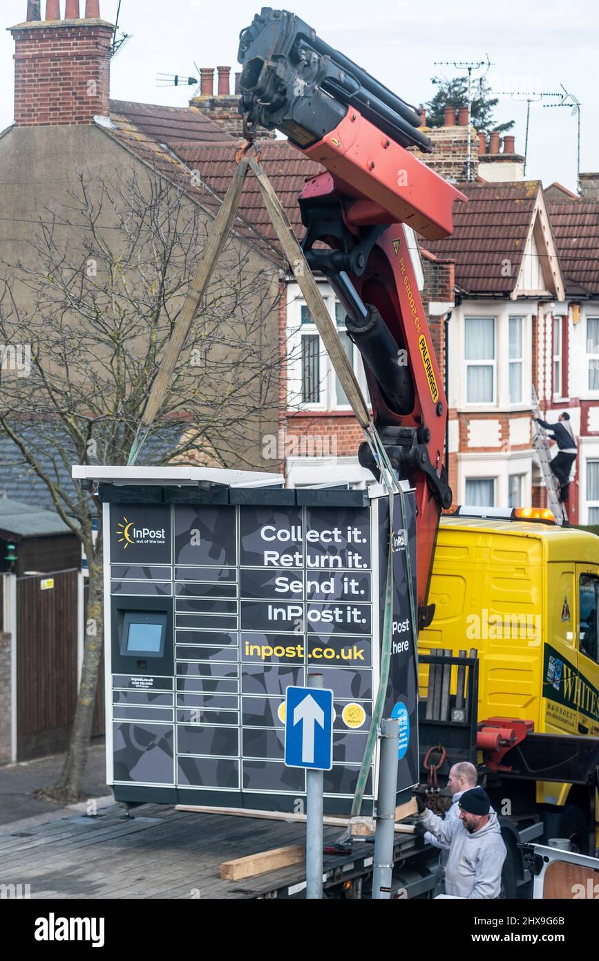 InPost automated parcel system being offloaded by crane to be installed at a local corner shop. External post self service system being delivered Stock Photo