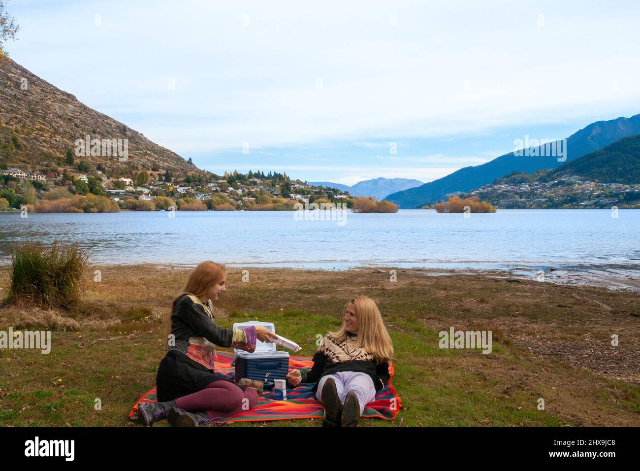 Young travel couple having picnic outdoor at Queenstown Lake Wakatipu South Island of New Zealand Stock Photo