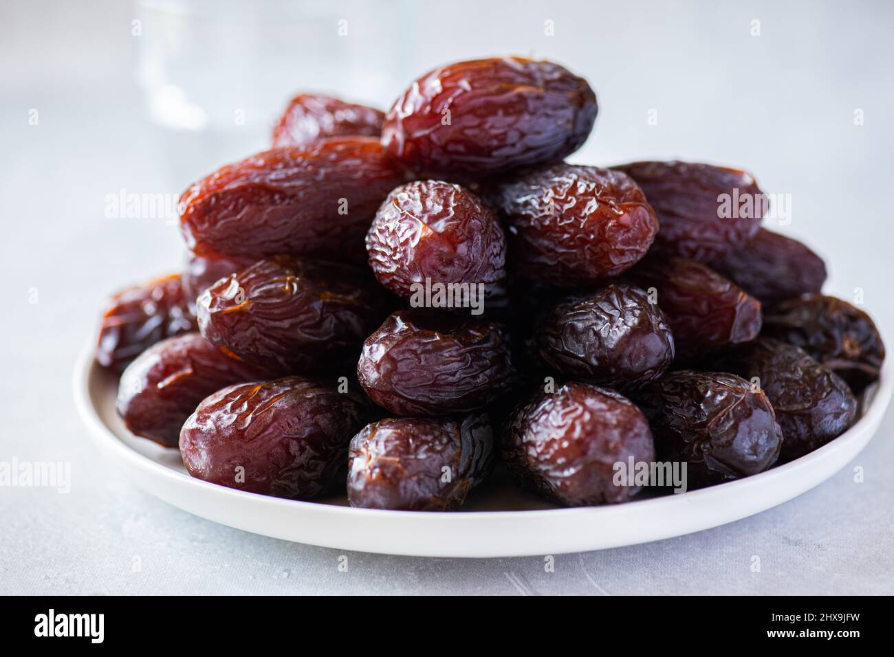 Close up of Medjoul dates in a white plate on a gray background. Stock Photo