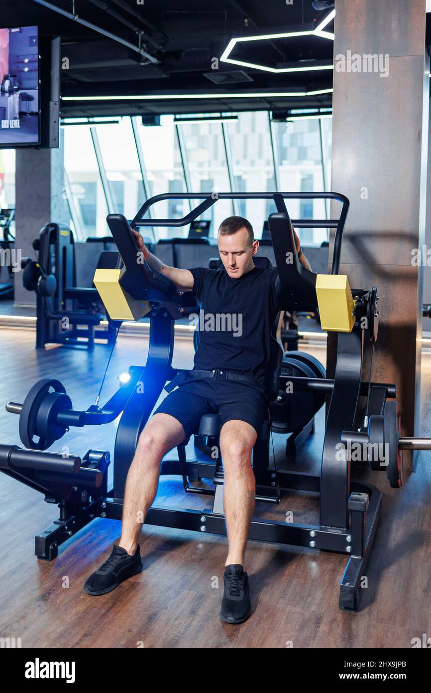 Attractive adult man doing exercises and lifting weights in the gym ...