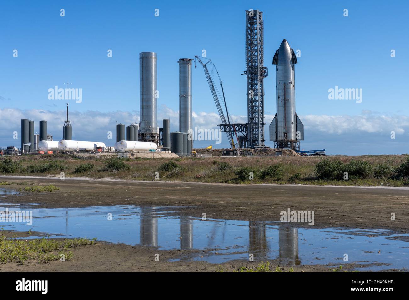 A Starship and two cylindrical Super Heavy Booster rockets by the SpaceX launch tower at Boca Chica, Texas.  The Starship is 160' tall, while the Supe Stock Photo