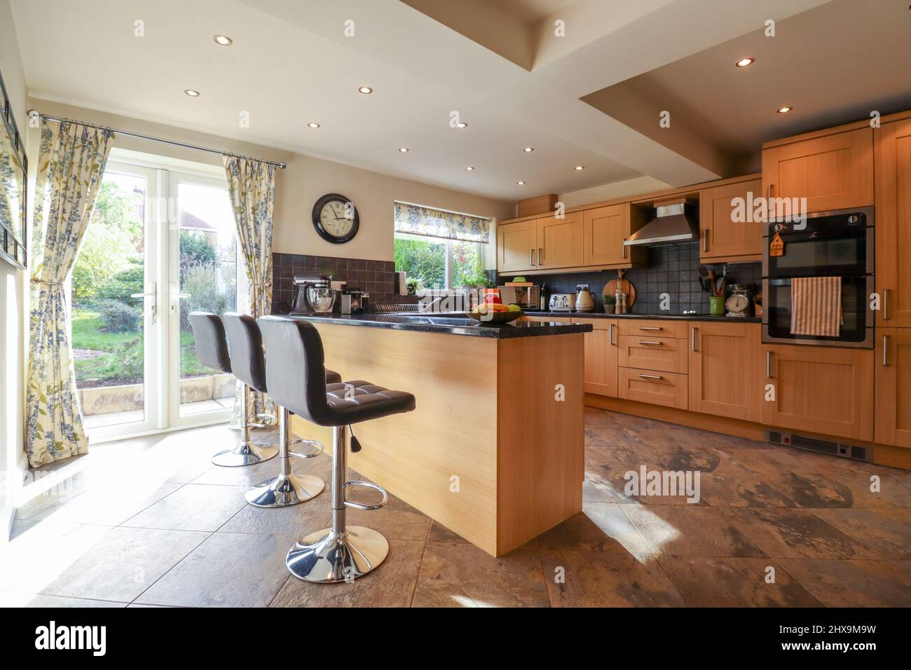Modern kitchen with wood effect kitchen, island with bar stools Stock