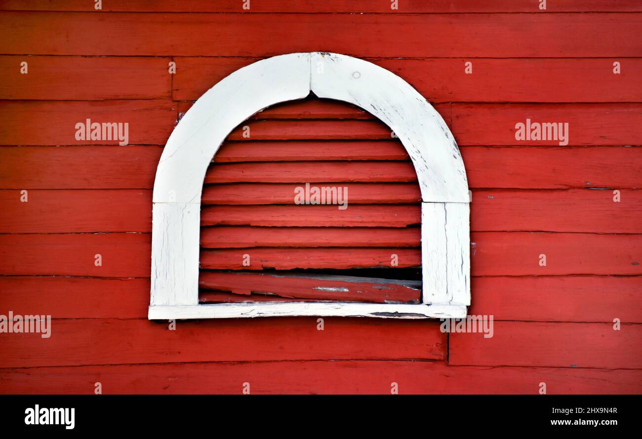 Rustic and rotting, arched window vent is outlined in white. Wall and