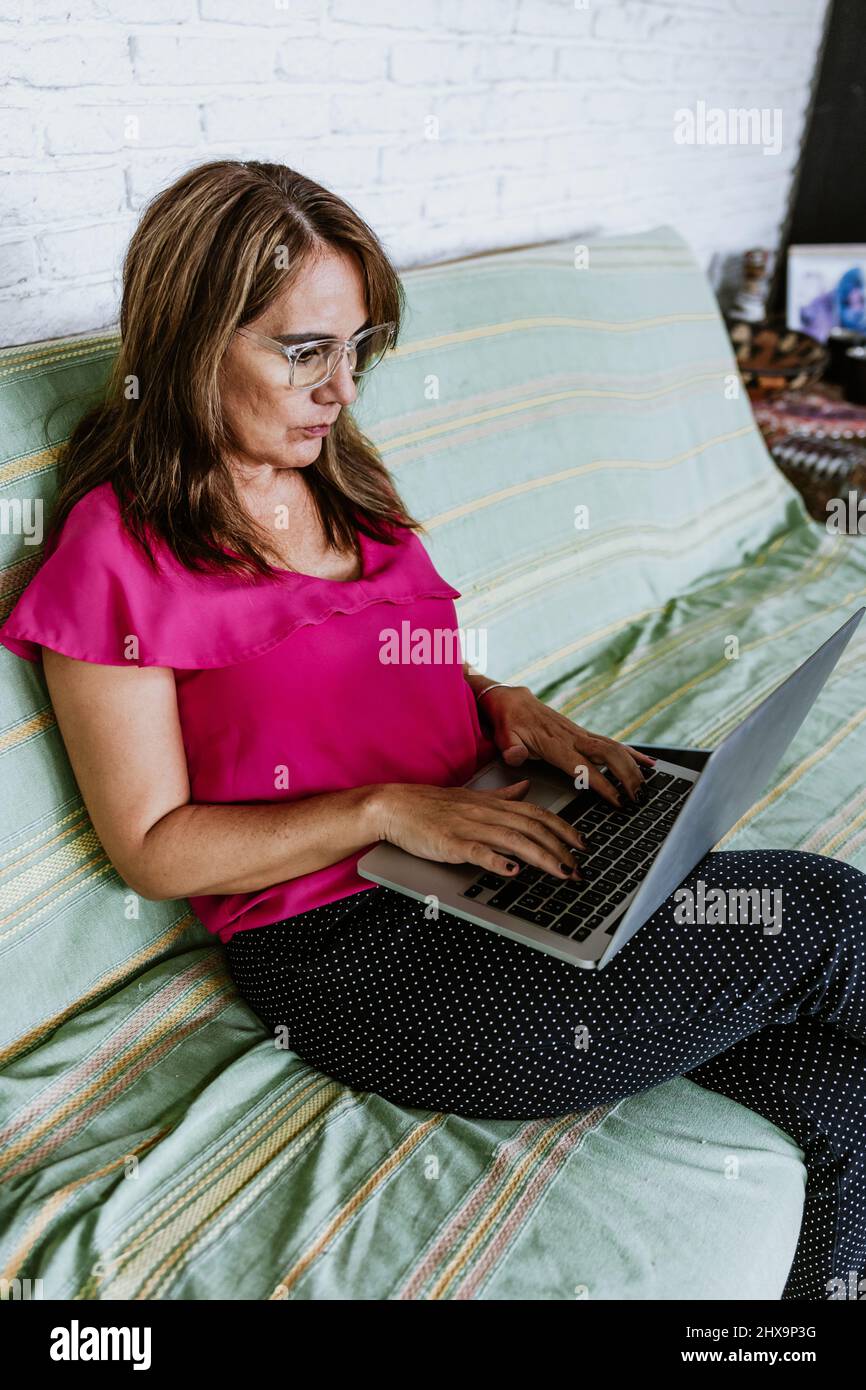 Senior hispanic woman middle age working with computer at home in sofa ...
