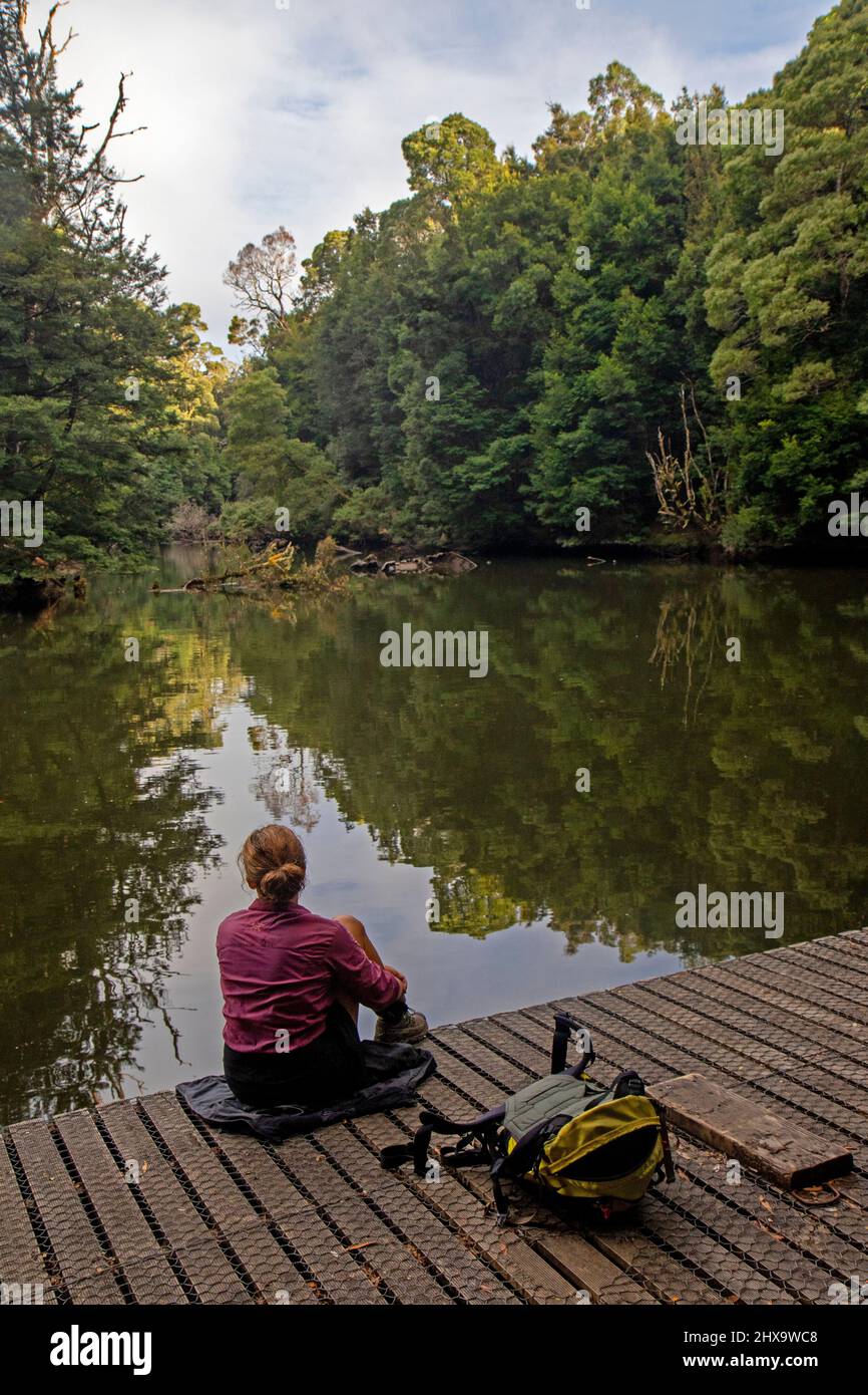 Woman sitting on a pontoon on the Savage River in the takayna/Tarkine rainforest Stock Photo