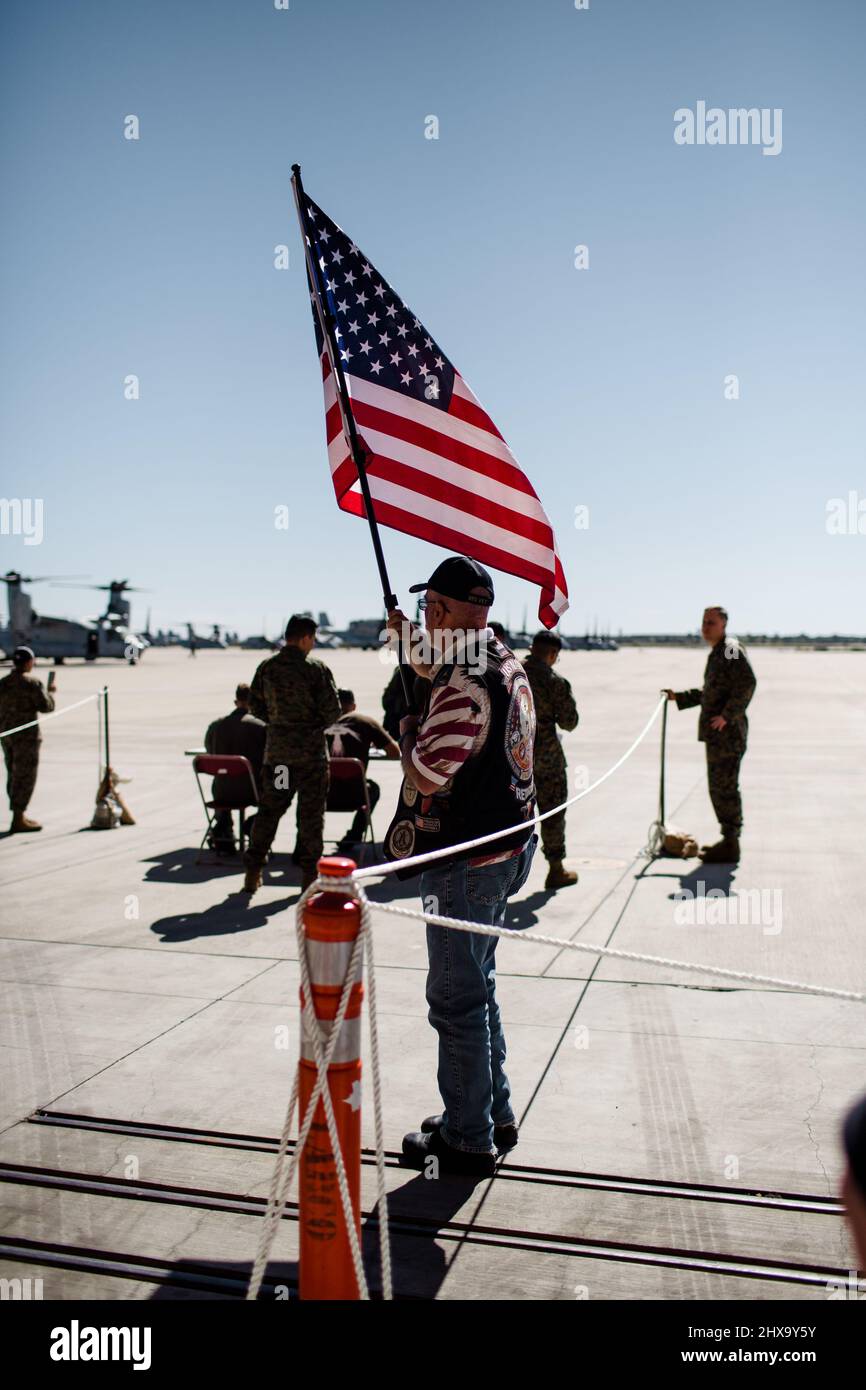 Military Vet Holding Flag & Welcoming Soldiers Home in San Diego Stock Photo