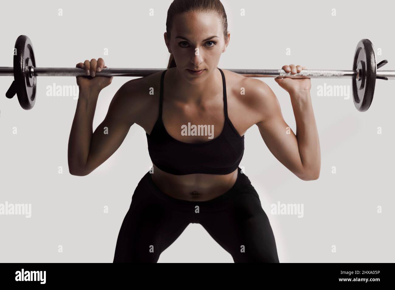 Tough young woman exercising with barbell. Determined female athlete  lifting heavy weights Stock Photo - Alamy