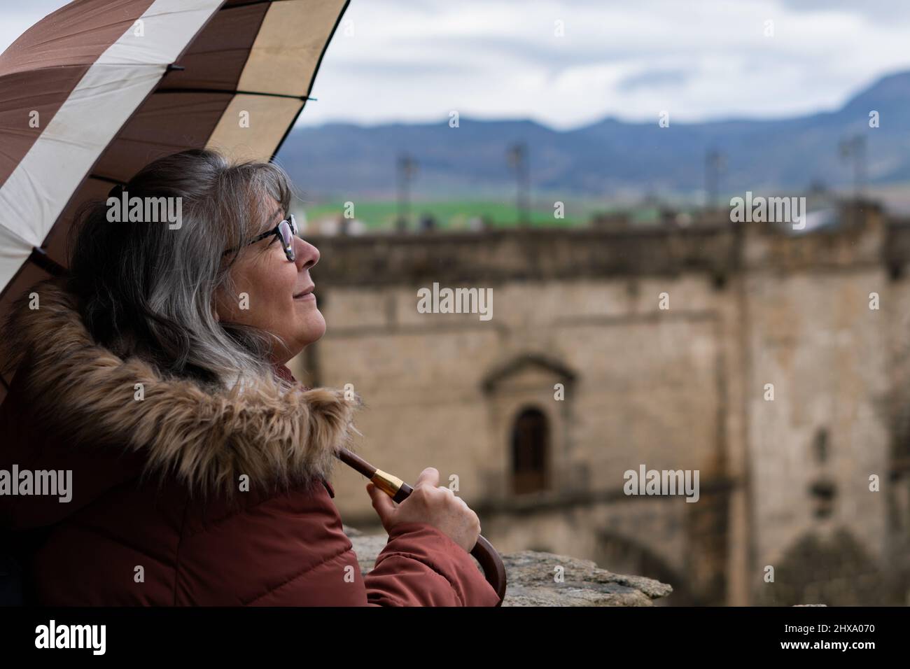 white-haired woman with umbrella in the rain Stock Photo