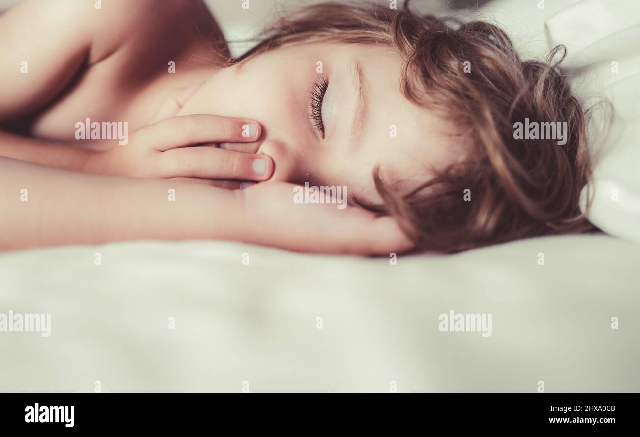 Little kids sleeping with her mouth open, snoring. Kid in bedroom sleep on bed with white sheet and pillow. Stock Photo