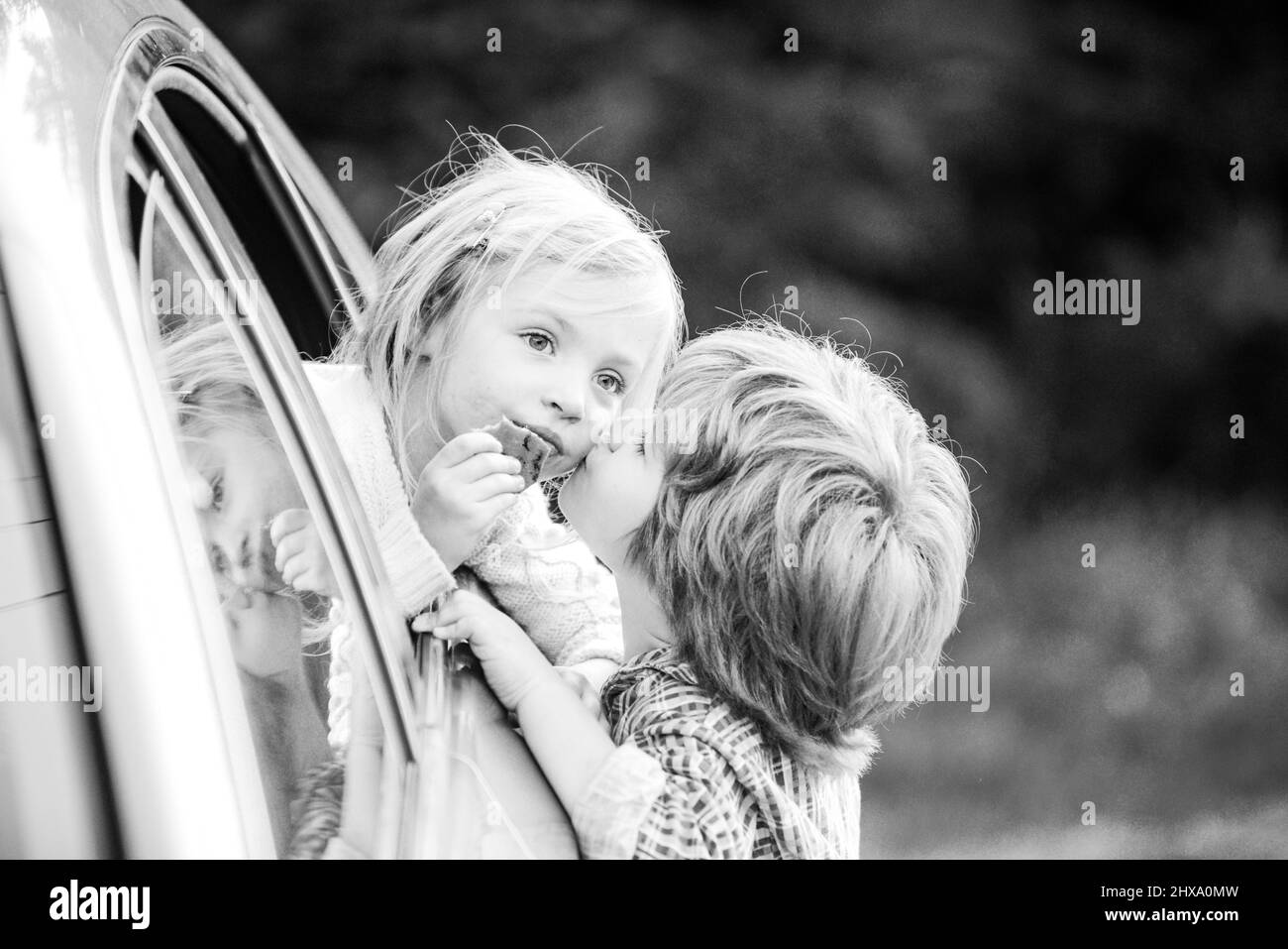 Two kids saying goodbye before car travel. Little boy gives kiss for cute girl. Good bye before car travel. Stock Photo