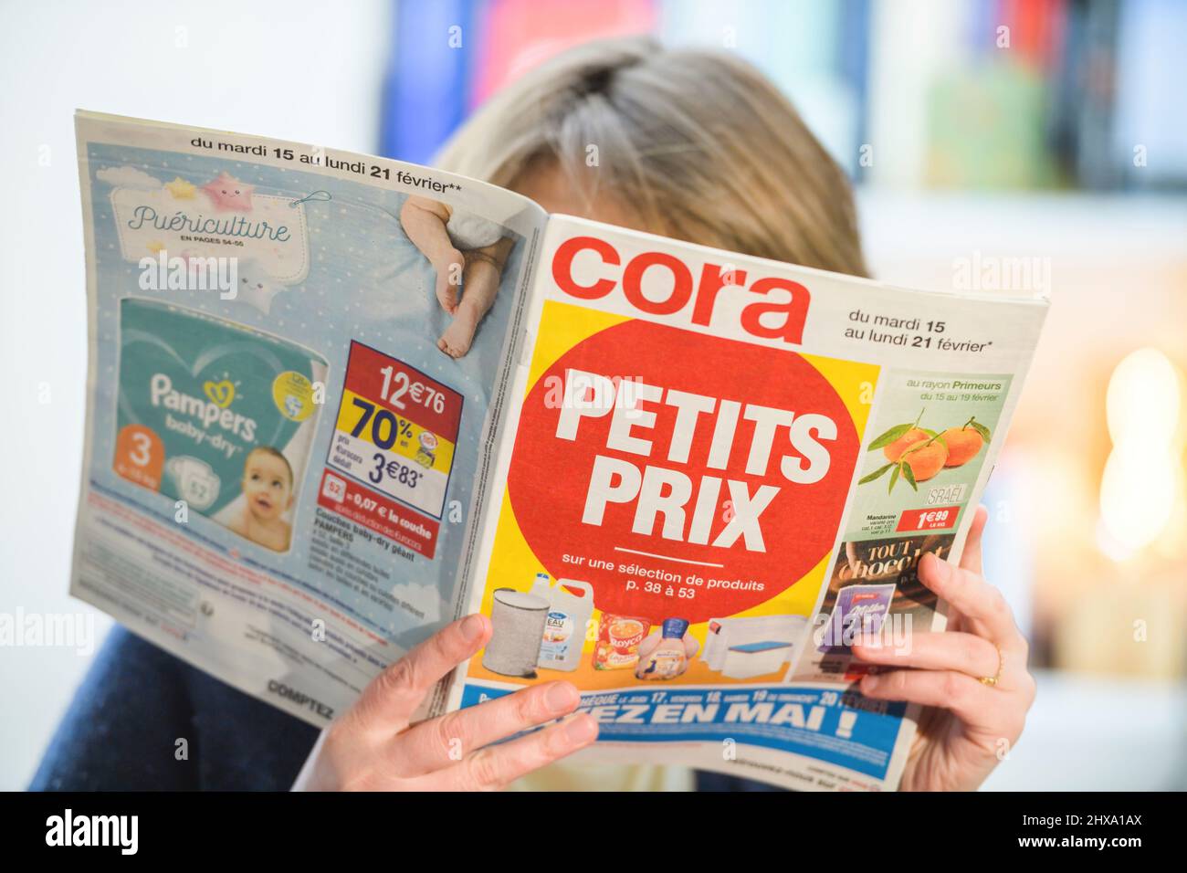 Paris, France - Feb 23, 2022: Woman reading Cora hypermarket special offer  leaflet flyer choosing best prices with large text Petit Prix translated as  Small prices Stock Photo - Alamy
