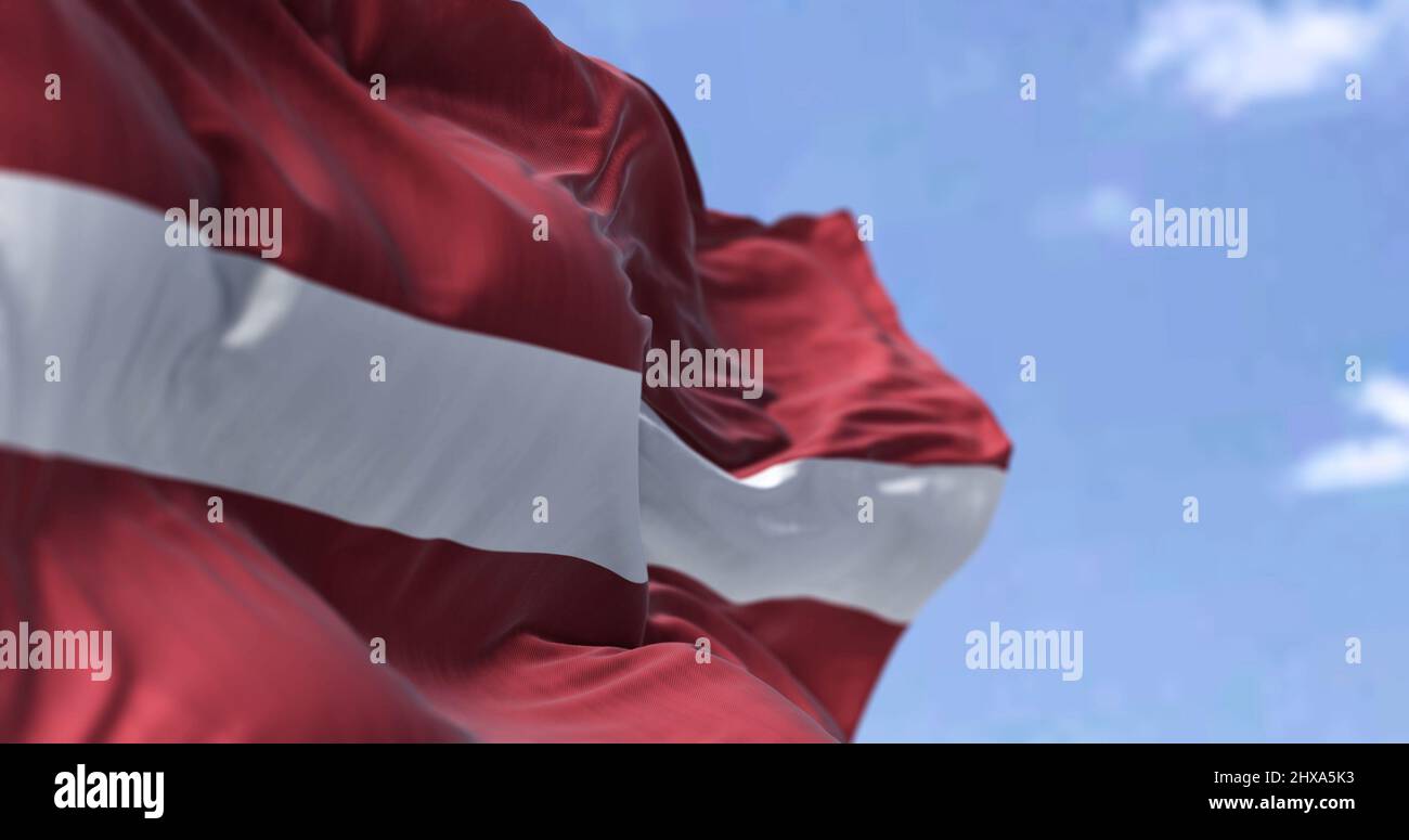 Detail of the national flag of Latvia waving in the wind on a clear day. Latvia is a country in the Baltic region of Northern Europe. Selective focus. Stock Photo