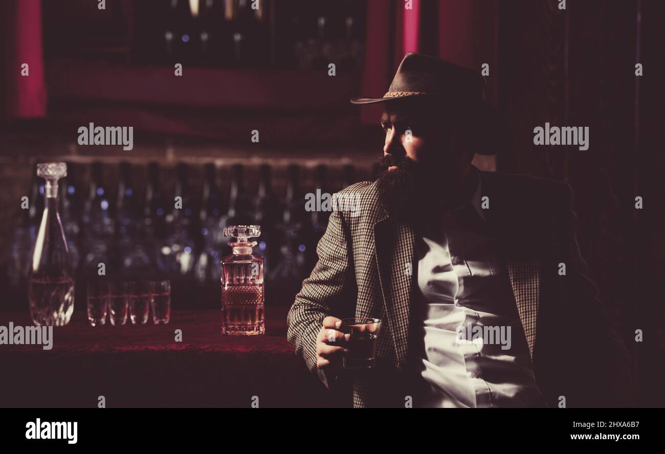 Old traditional whiskey drink - gentlemans beverage. Hipster male with stylish beard drinking beer sitting at the bar. Stock Photo