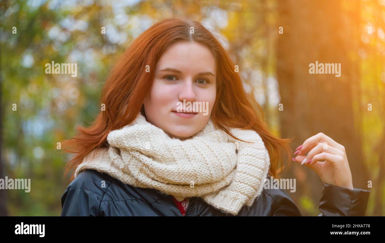 portrait of a red-haired smiling girl in a jacket and scarf ...