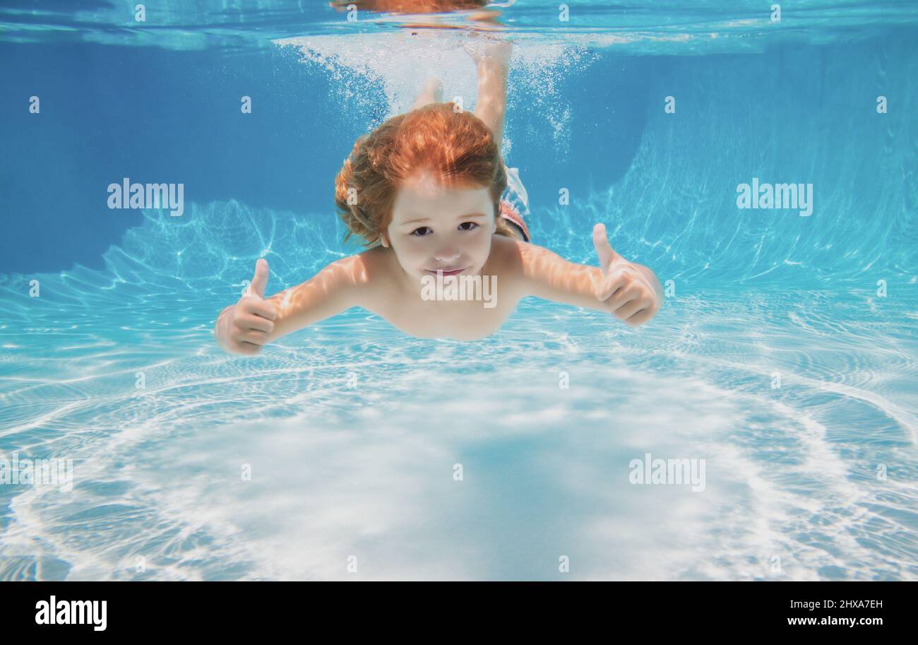 Child swimming underwater with thumbs up. Underwater kid swim under