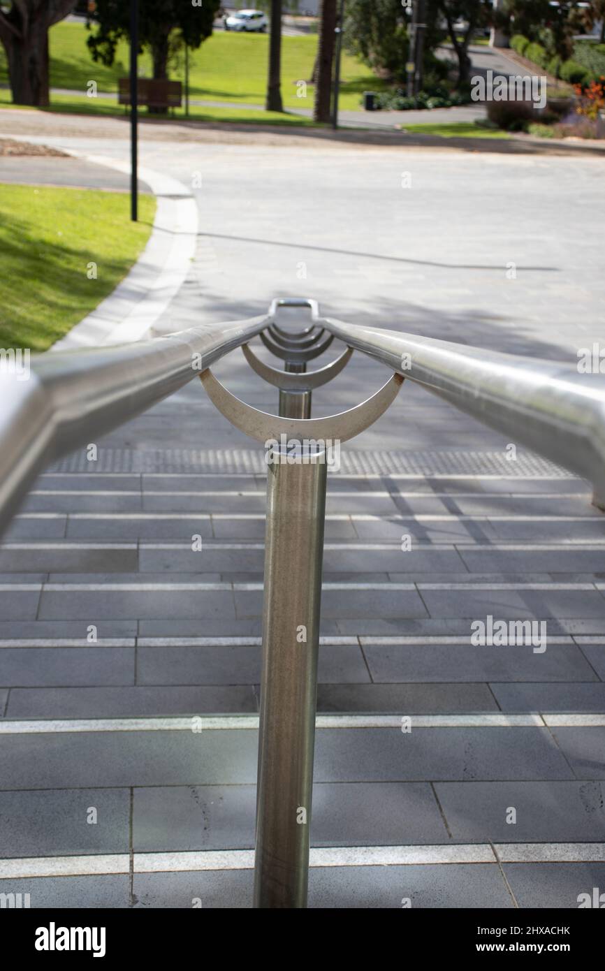 Double metal railing going down stairs into a park. Stock Photo