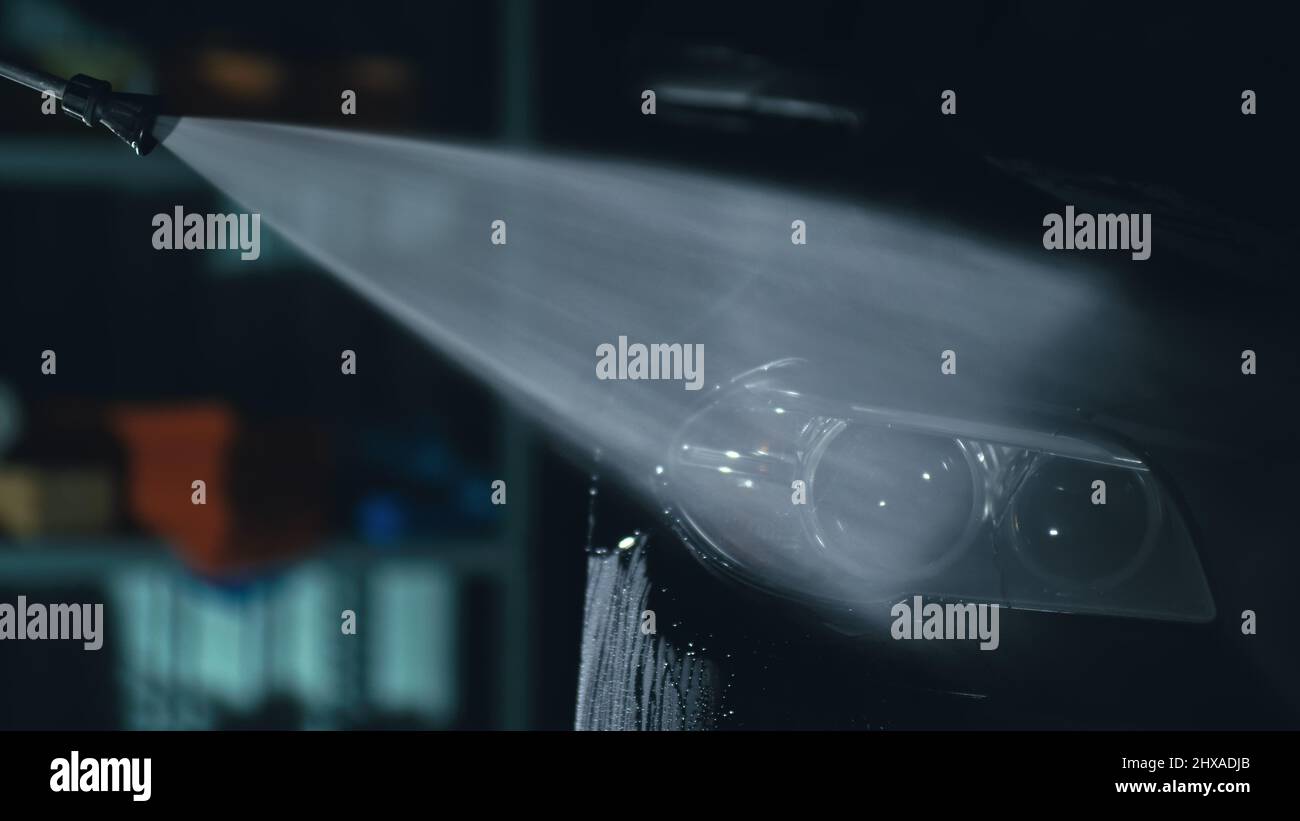 Car headlight wash. Washing modern vehicle body by high pressure jet