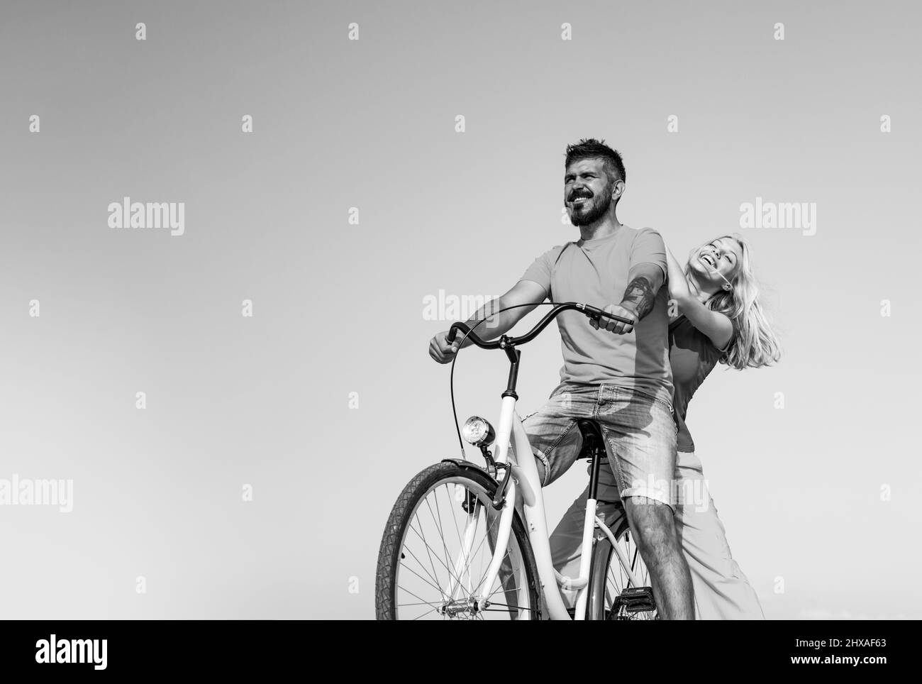 Young riders enjoying themselves on trip. Stylish and loving couple enjoying. Couple in love riding a bike. Attractive couple on a bike ride on a Stock Photo