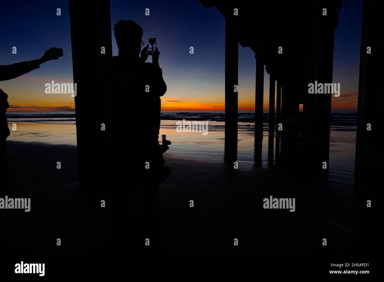 La JOLLA, CALIFORNIA. February 9, 2021. Visitors photographing Scripps Pier in La Jolla, California at sunset with orange and blue sky.  Photo: Mark J Stock Photo