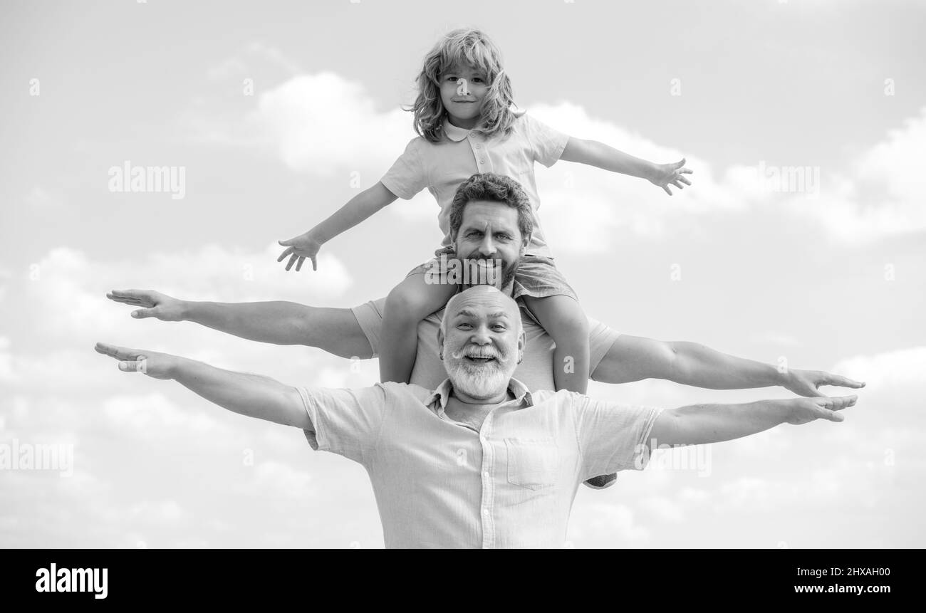 Father, son and grandfather happy multi genration family with aising hands or open arms flying on sky. Generations men. Stock Photo