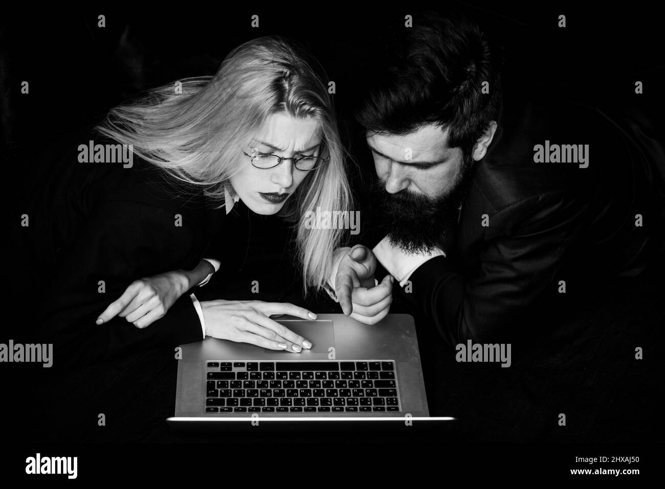 Couple of young coworkers discussing project over a laptop, team of businesspeople with computer. Stock Photo